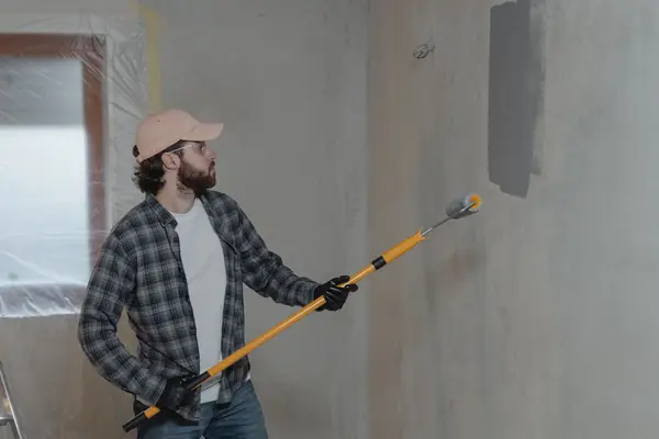 Painter rolling grey paint onto an interior wall in Fort Wayne